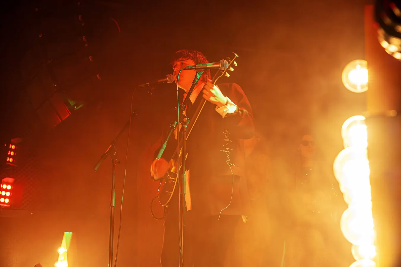 Guitarist performing on stage in orange stage smoke