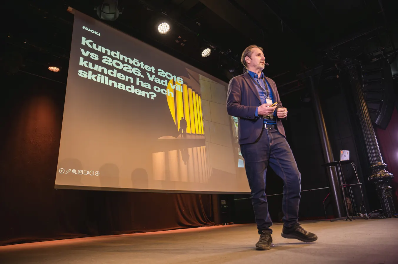 Speaker on stage in front of a large presentation screen