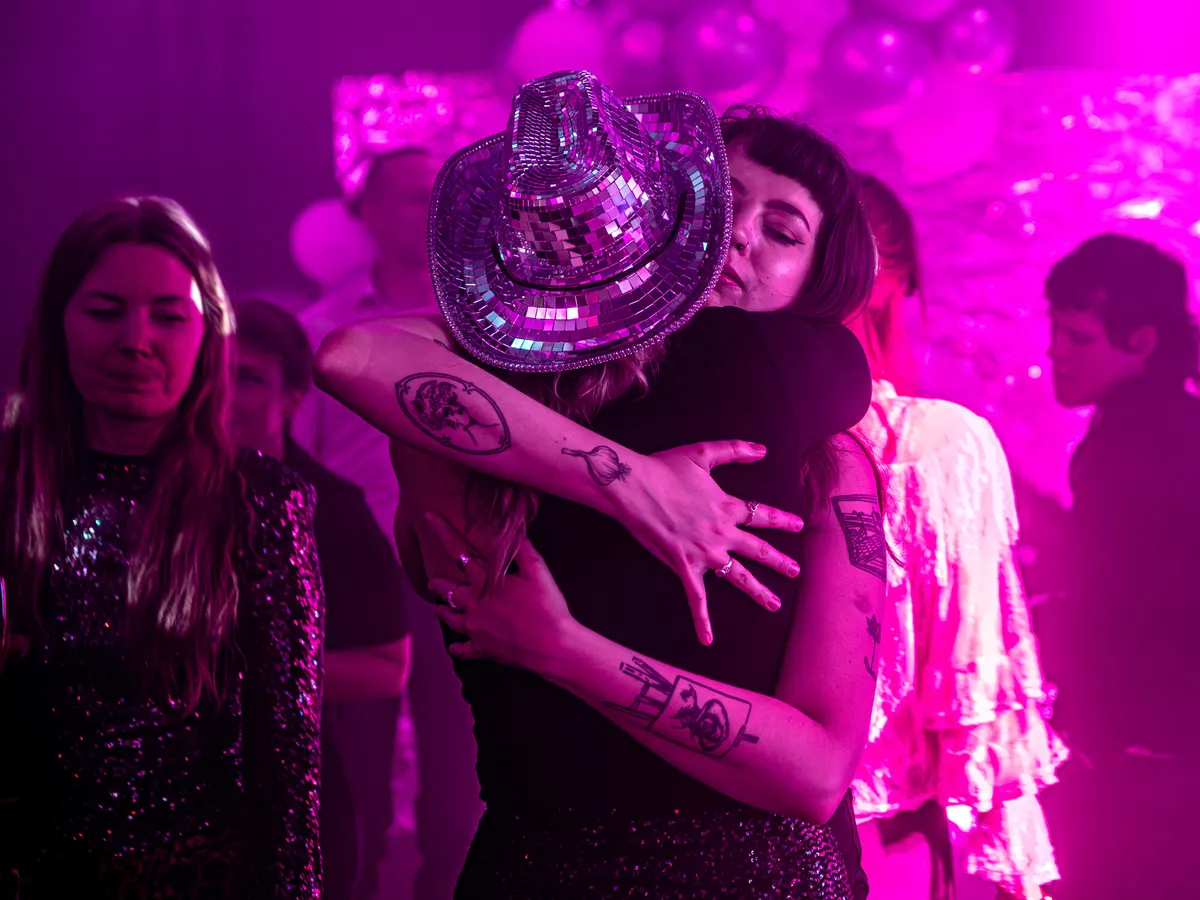 Two guests hugging at an after-party under pink light