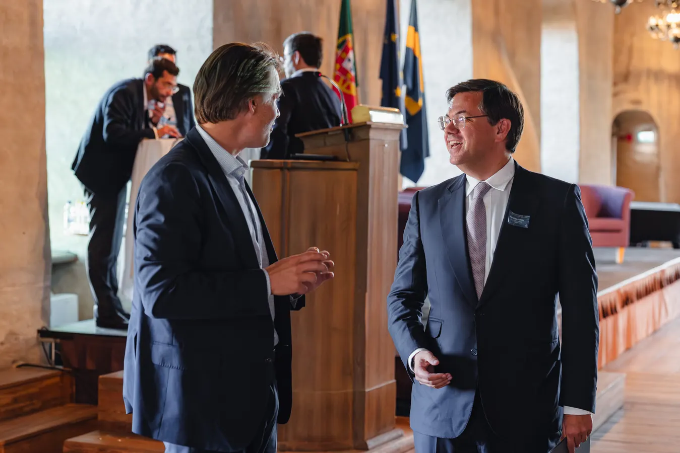 Two men in suits talking beside a lectern