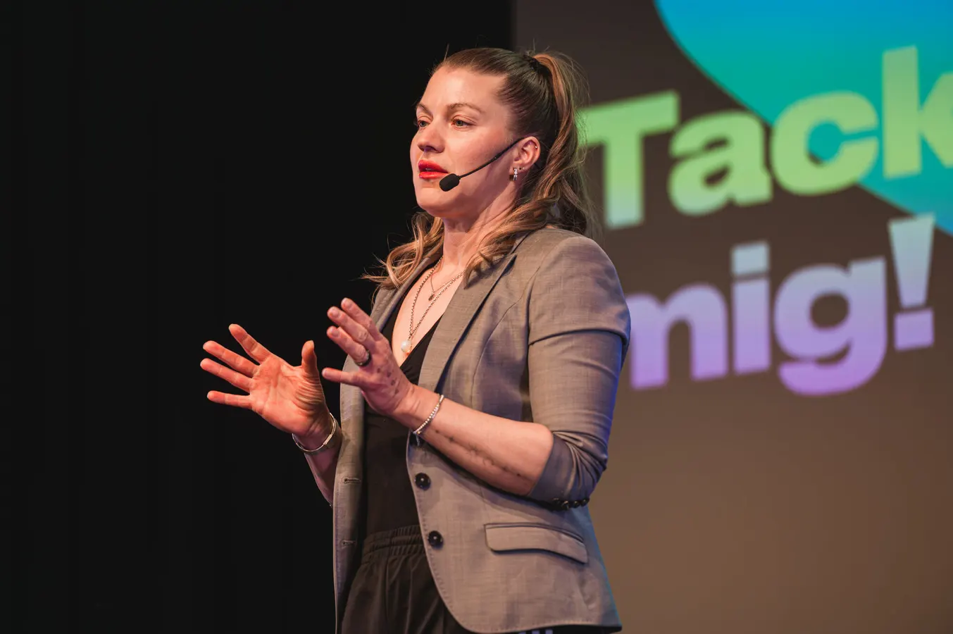 Speaker with a headset microphone gesturing on stage