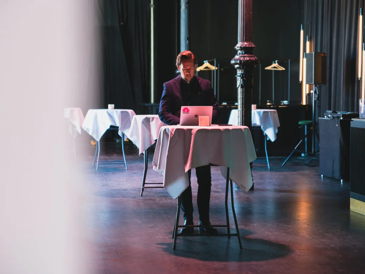 Man working at a laptop at a standing table before an event