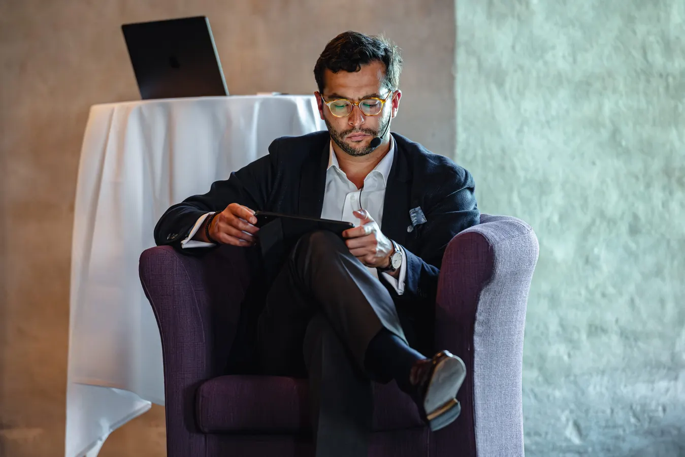 Speaker seated in an armchair with a tablet during a panel