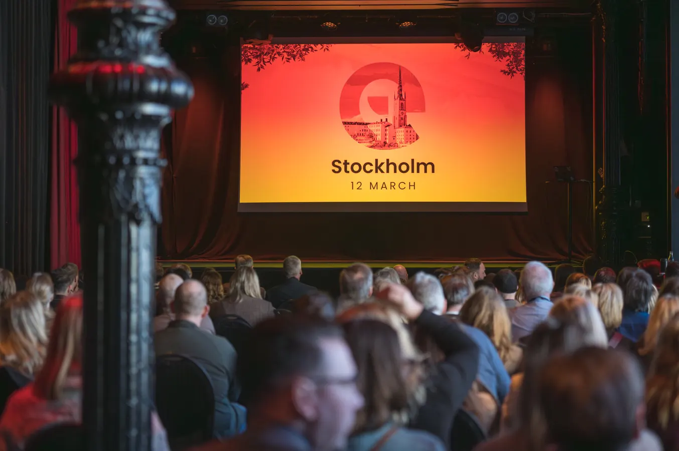 Audience facing a screen that reads Stockholm, 12 March