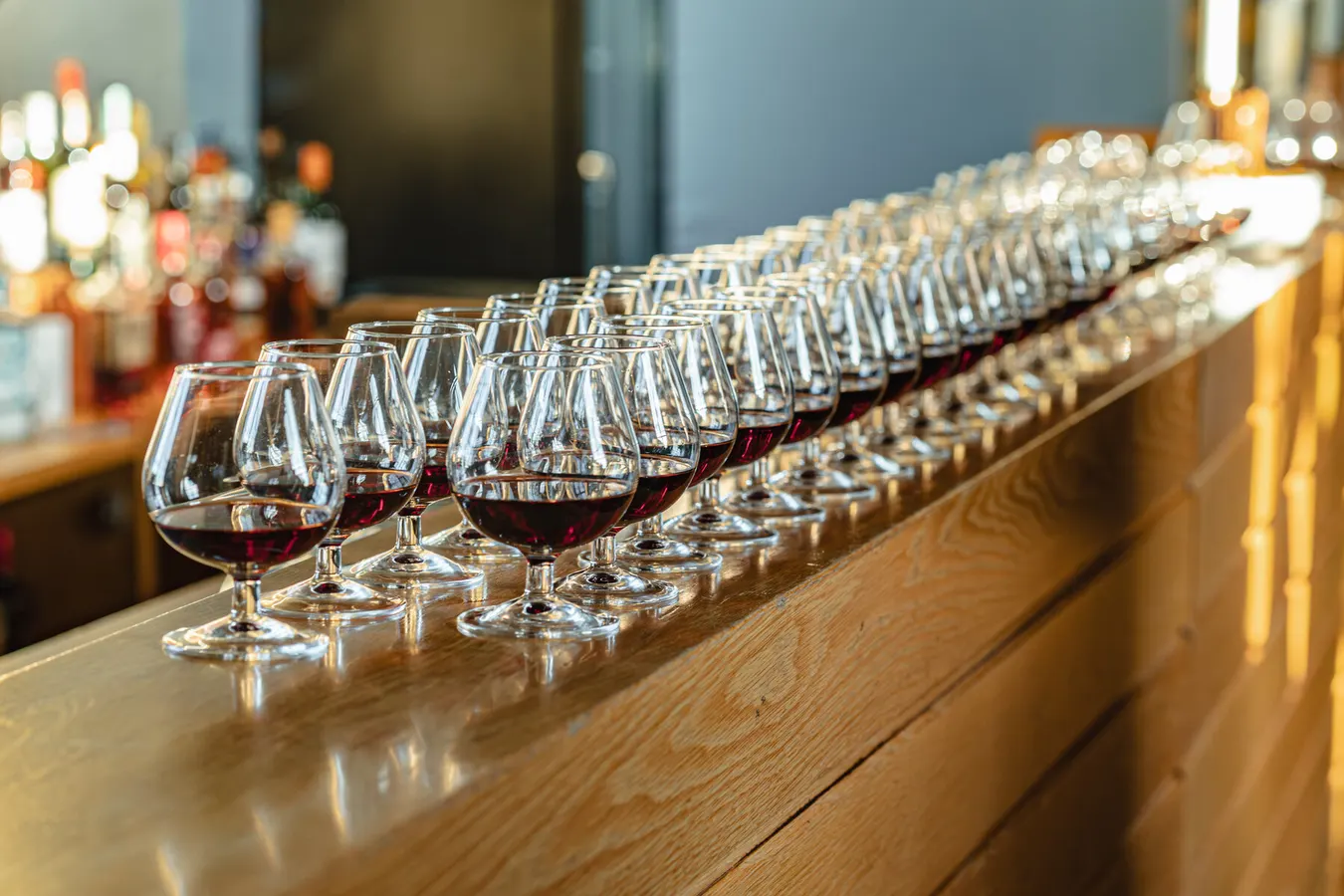 Row of wine glasses lined up on a wooden bar