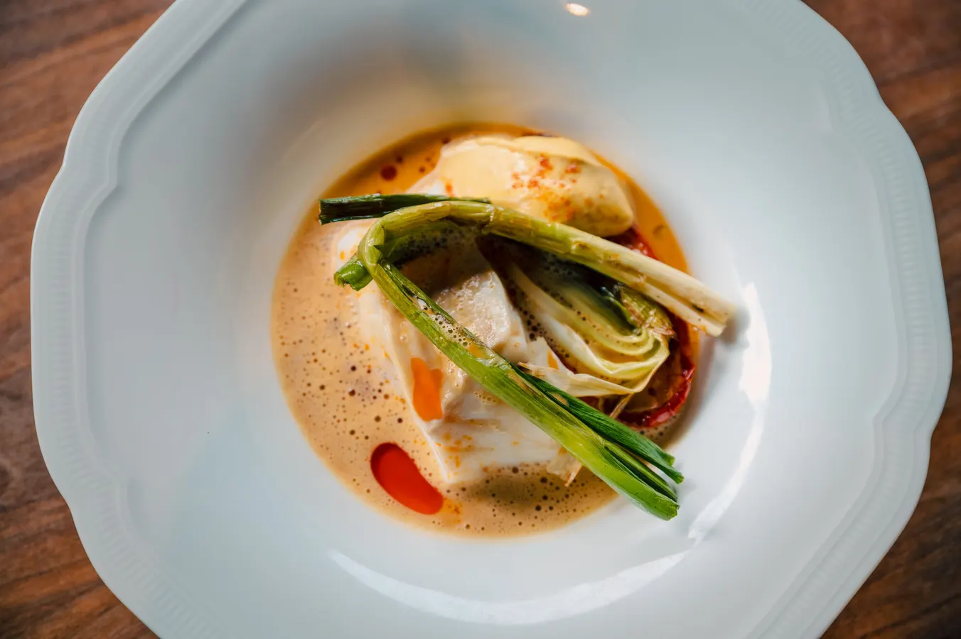 Fish with spring onion in a foamy sauce, seen from above