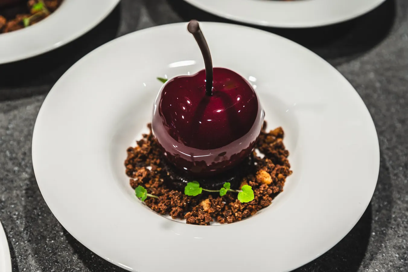 Glossy cherry-shaped dessert on chocolate crumble