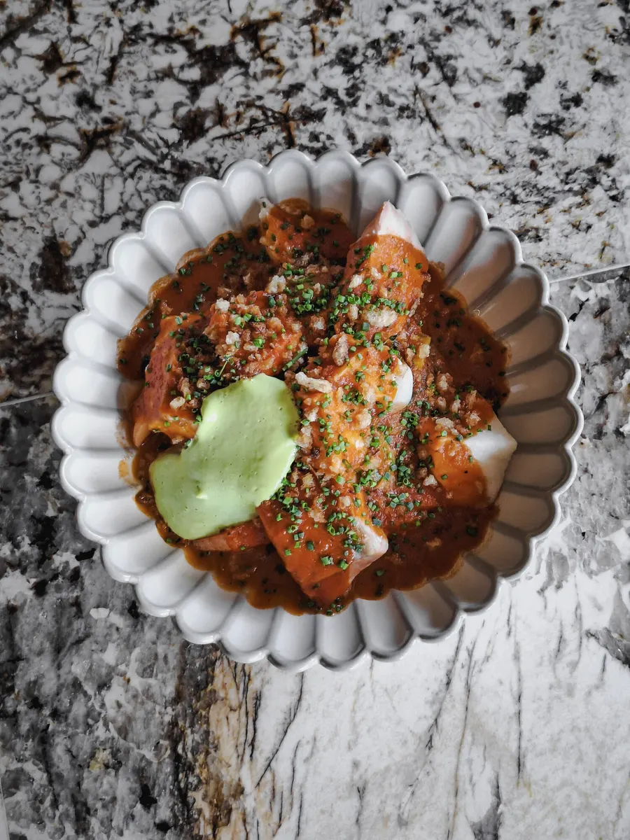 Dish in red sauce served in a scalloped bowl on marble