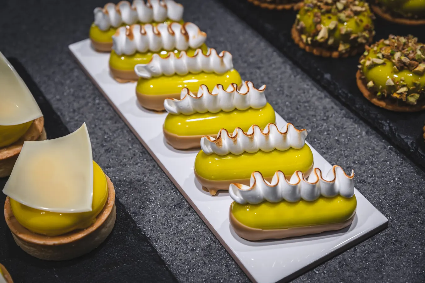 Row of lemon éclairs with torched meringue